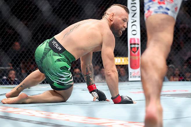지난 12일 UFC 329에서 상대 맥스 할러웨이에게 발차기 후 스스로 쓰러진 코너 맥그리거가 엉거주춤한 동작으로 일어서려 하고 있다. [게티이미지]