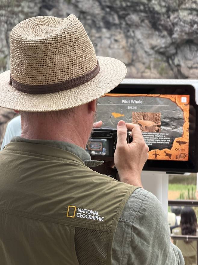 A participant in the 8th World Heritage Site Managers' Forum examines the petroglyphs through an XR (extended reality) device installed across from the site on July 17. KOREA HERITAGE SERVICE