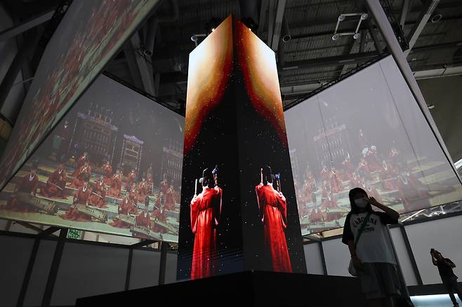 A visitor takes a photo of a digital recreation of jerye, or the grand royal ancestral rites from the Joseon Dynasty (1392-1910), on July 20, displayed at K-Heritage House set up at the Bexco convention hall in Busan for the 48th session of the Unesco World Heritage Committee. YONHAP