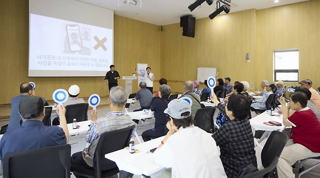 지난 21일 경기 동두천장애인복지관에서 열린 SK텔레콤의 ‘찾아가는 서비스’ 교육에 참석한 농아인들이 손팻말을 들고 보이스피싱에 대한 강사의 질문에 답하고 있다.  SK텔레콤 제공
