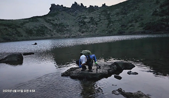 한라산 백록담 분화구 안으로 무단으로 들어가 물을 떠먹는 등산객의 모습. [제주도의회]