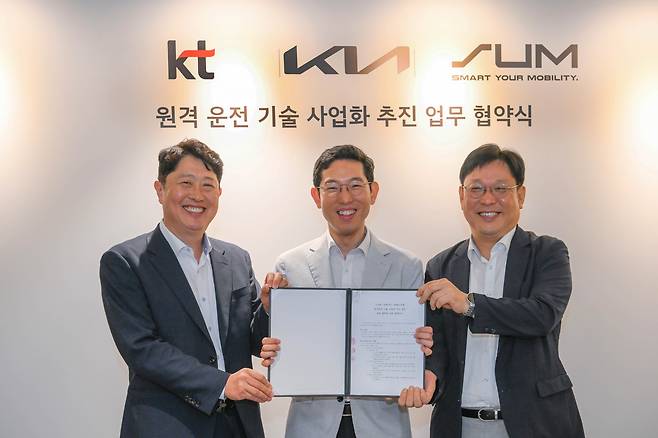 23일 서울 양재동 기아 본사에서 서상규(왼쪽부터) KT 기업사업1담당 상무, 강주엽 기아 신사업기획실 상무, 현영진 에스유엠 대표가 ‘원격 운전 기술 사업화 추진을 위한 업무협약(MOU)’을 체결하고 기념사진을 촬영하고 있다. [기아 제공]