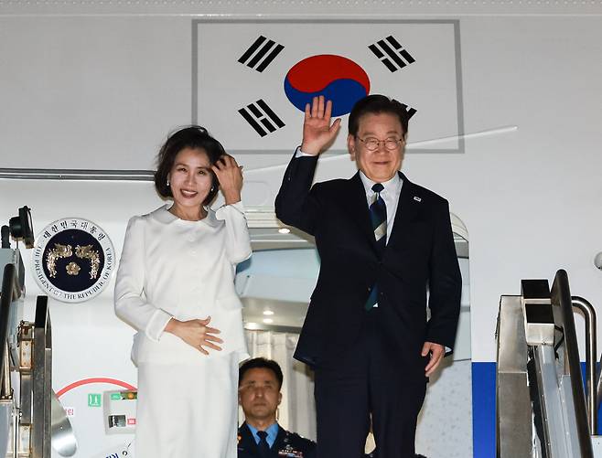 AI 서밋 일정을 마친 이재명 대통령과 김혜경 여사가 25일(현지시간) 미국 샌프란시스코 국제공항에서 공군 1호기에 올라 인사하고 있다./뉴스1
