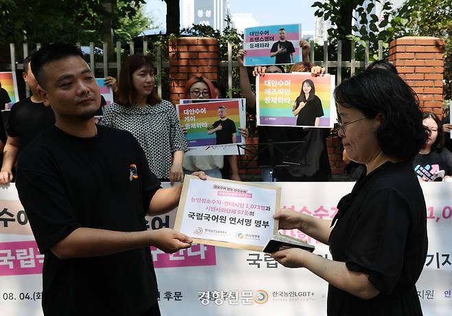 한국농인LGBT+ 우지양 상임활동가가 4일 서울 강서구 국립국어원 앞에서 ‘혐오수어 없는 한국수어’를 요구하는 기자회견을 마친 뒤 최혜원 국립국어원 수어점자진흥과 과장에게 농인성소수자·연대시민 1073명과 57개 시민사회단체의 연서명 명부를 전달하고 있다. 강윤중 선임기자