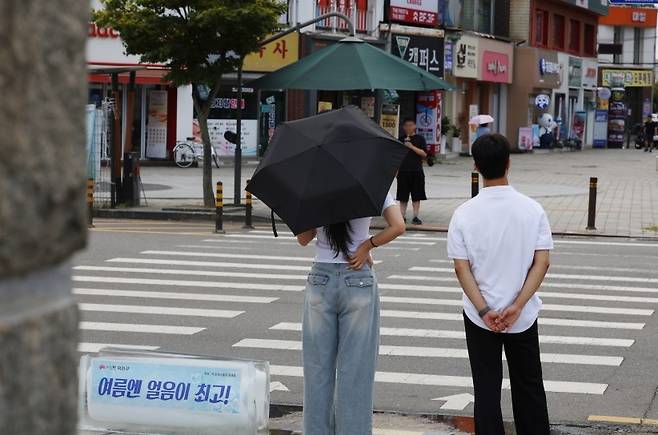 '여름엔 얼음이 최고?' (전주=연합뉴스) 정경재 기자 = 폭염 중대경보가 내려진 5일 전북 전주시의 번화가인 전북대 구정문 앞에서 시민들이 교통신호를 기다리고 있다. 한쪽에만 그늘막이 설치돼 있다. 2026.8.5