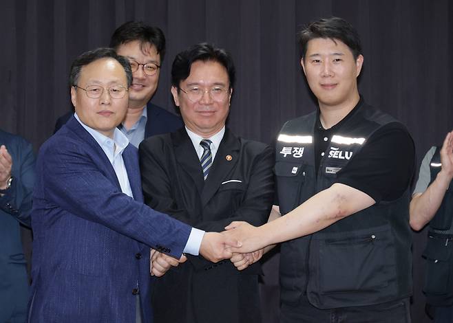 지난 5월20일 경기 수원시 장안구 경기고용노동청에서 열린 삼성전자 임금 협상을 마친 후 (왼쪽) 여명구 삼성전자 디바이스솔루션(DS) 피플팀장과 최승호 삼성그룹 초기업노동조합 삼성전자지부(초기업노조) 위원장이 김영환 고용노동부 장관과 손을 맞잡고 있다. [공동취재]
