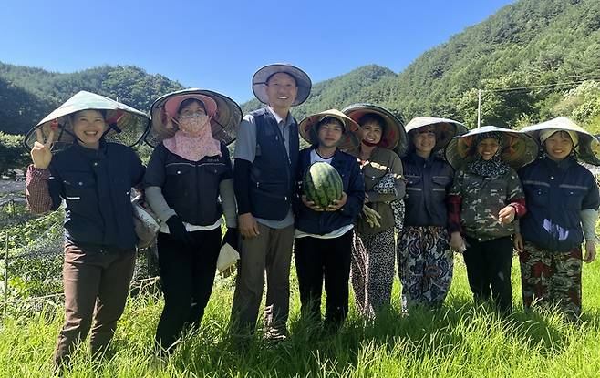 박상철 봉화군 법전면 소천1리 이장(왼쪽 세번째)이 외국인 계절근로자 사업을 통해 함께 일한 베트남 근로자들과 수박밭에서 수확한 수박을 들고 기념촬영을 하고 있다. <황준오기자>