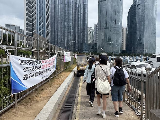 요트 탑승하러 가는 관광객 옆에 붙은 보험 미적용 현수막 [손형주 기자]