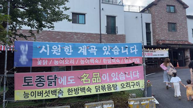 A restaurant selling chicken soup has a large banner reading, "We have a valley" in front of the store. WOO JI-WON