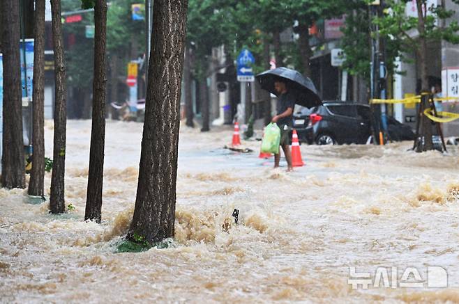 [거제=뉴시스] 차용현 기자 = 기록적인 폭우가 쏟아진 17일 오후 흙탕물이 거세게 흘러 넘치는 도로를 한 시민이 건너고 있다. 2026.08.17. con@newsis.com