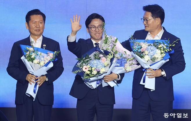 더불어민주당 김민석 신임 대표(가운데)가 17일 대전 유성구 대전컨벤션센터에서 열린 전국당원대회에서 최종 득표율 54.08%로 임기 2년의 새 대표로 선출된 후 웃으며 인사하고 있다. 2위 정청래 의원(왼쪽)은 굳은 표정으로 정면을 응시하고 있는 반면 3위 송영길 의원은 김 대표를 바라보며 축하하고 있다. 대전=박형기 기자 oneshot@donga.com