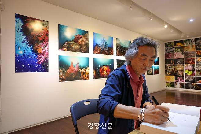 전시 시작일인 19일 김호웅 사진가가 서울 종로구 인사동 갤러리 인덱스에서 책에 서명하고 있다. 이준헌 기자