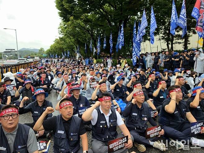 금속노조 조합원들이 도로에 앉아 집회를 이어가고 있다. 참가자들이 '단결투쟁' 등이 적힌 머리띠를 두르고 구호를 외치고 있다.[사진=윤경진 기자]