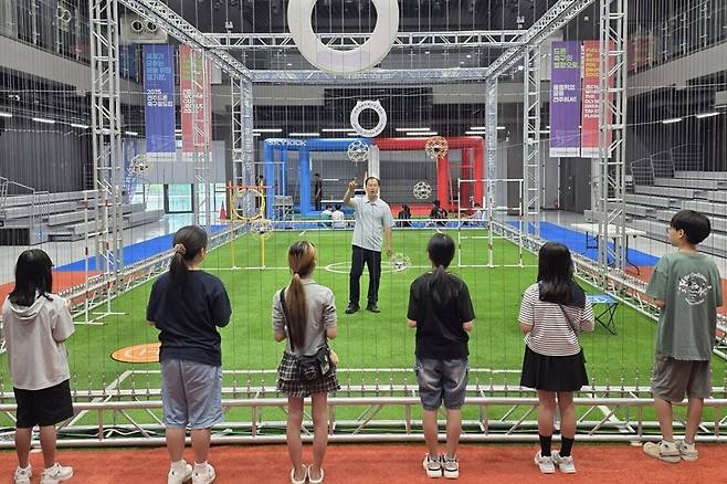 전북 전주국제드론스포츠센터에서 드론축구 초등학생 연계 체험 프로그램 참가 학생들이 드론축구 경기 방식에 대한 설명을 듣고 있다. 전주시 제공