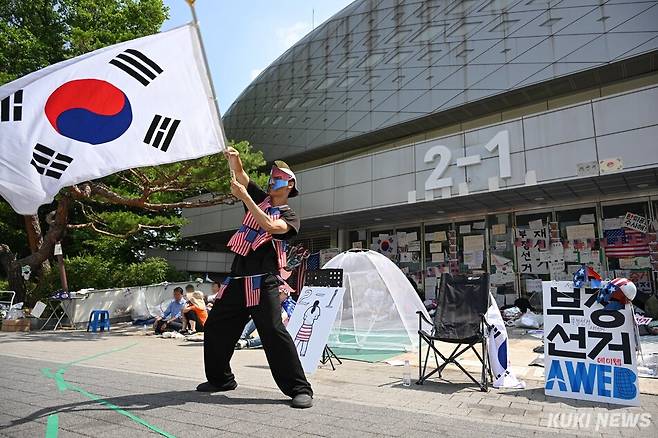 투표용지 부족 사태를 규탄하기 서울 송파구 올림픽공원 핸드볼경기장 앞을 찾은 박경환(32)씨가 대형 태극기를 흔들고 있다. 임은재 기자
