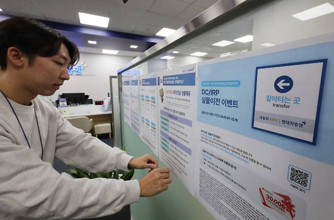 서울 한 증권사 영업점에서 관계자가 퇴직연금 실물이전 관련 홍보물을 부착하고 있다. 사진=연합뉴스