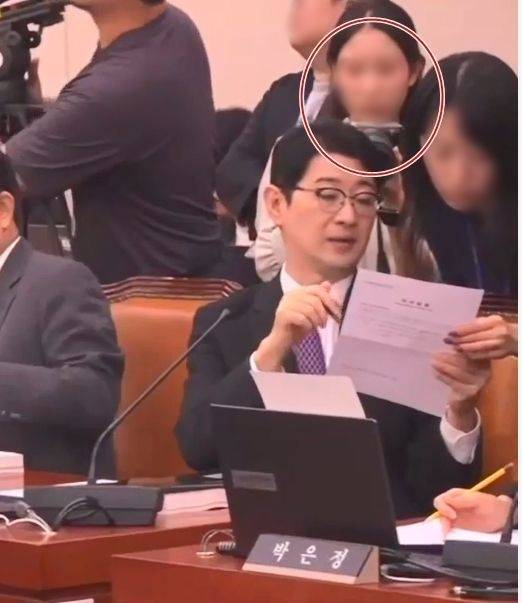 지난 15일 김승원 법무부 장관 후보자의 인사청문회에서 한 여성이 주진우 국민의힘 의원이 들고 있는 서류를 촬영하는 듯한 모습이 포착됐다. 해당 여성은 김 후보자 의원실의 보좌진으로 밝혀졌다. [펀앤마이크 유튜브 캡처]