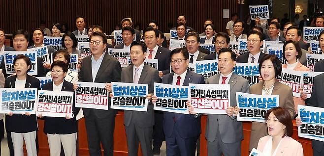 장동혁 국민의힘 대표와 정점식 원내대표를 비롯한 의원들이 17일 서울 여의도 국회에서 열린 의원총회에서 ‘철거민 4성 딱지 강신철 OUT’, ‘법치 상실 김승원 OUT’이라고 적힌 피켓을 들고 구호를 외치고 있다. 뉴스1