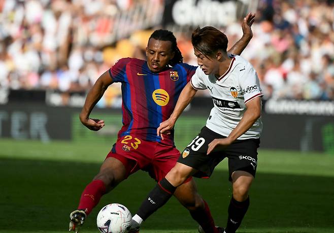 Barcelona's French defender #23 Jules Kounde fights for the ball with Valencia's Japanese defender #39 Ryunosuke Sato during the Spanish league football match between Valencia CF and FC Barcelona at Mestalla Stadium in Valencia on September 6, 2026. (Photo by JOSE JORDAN / AFP)<저작권자(c) 연합뉴스, 무단 전재-재배포, AI 학습 및 활용 금지>