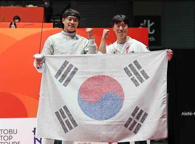 ▲ 23일 일본 아이치현 도코나메 아이치 스카이 엑스포에서 열린 2026 아이치·나고야 아시안게임 남자 사브르 개인전 결승 경기. 한국 오상욱(왼쪽)이 중국의 선천펑을 상대로 승리하며 금메달을 획득한 뒤 태극기를 들고 파이팅을 외치고 있다. 2026.9.23 연합뉴스