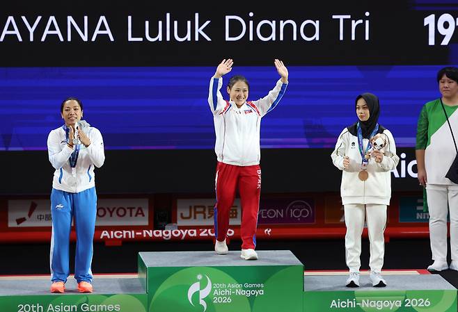 이날 일본 나고야 중소기업진흥회관에서 열린 2026 아이치·나고야 아시안게임 역도 여자 49㎏ 결승에서 금메달을 획득한 북한 리성금이 시상대에 오르며 인사하고 있다. / 사진 = 연합뉴스