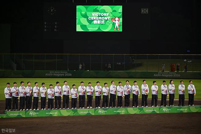 한국 야구 대표팀 선수들이 27일 일본 아이치현 도요하시 시민야구장에서 열린 2026 아이치·나고야 아시안게임 야구 시상식에서 금메달을 목에 걸고 태극기가 게양되는 것을 바라보고 있다. 한국은 결승에서 일본을 3-1로 꺾고 5개 대회 연속 금메달을 차지했다. 도요하시=하상윤 기자