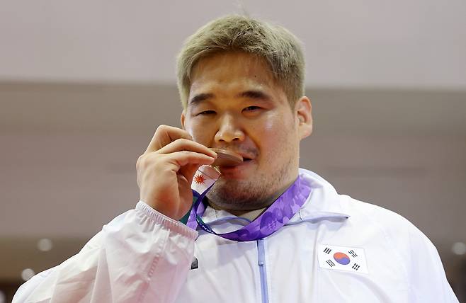 김민석이 30일 일본 나고야 이나에 스포츠센터에서 열린 2026 아이치·나고야 아시안게임 레슬링 남자 그로코로만형 130kg급에서 동메달을 차지한 후 메달을 깨물고 있다. 연합뉴스
