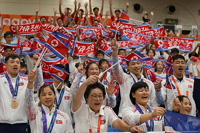 재일본조선인총연합회(조총련) 응원단이 지난달 28일 일본 나고야시 중소기업진흥회관에서 열린 2026 아이치·나고야 아시안게임 역도 남자 85kg급 시상식이 끝난 뒤 금메달을 딴 로광렬 등 북한 선수단과 함께 응원 구호를 외치고 있다. 사진 맨 앞줄 왼쪽에서 두 번째, 안경 쓴 인물이 김춘희 북한 역도 대표팀 감독이다. 나고야=하상윤 기자