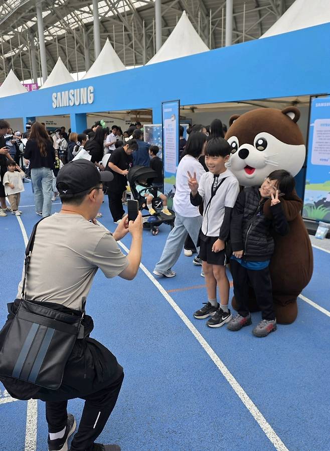 3일 경기 용인시 용인미르스타디움에서 열린 ‘2026 용인 사이버 과학축제’에 마련된 삼성전자 부스에서 지역 청소년들이 친환경 캐릭터 ‘달수’와 기념 촬영을 하고 있다. 삼성전자