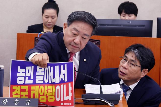 7일 국회에서 열린 농림축산식품해양수산위원회 국정감사에서 강승규 국민의힘 의원이 노트북에 붙어 있던 "농민 몰아내서 결국 태양광이냐"라고 쓰인 피켓을 떼어내고 있다. 뉴스1