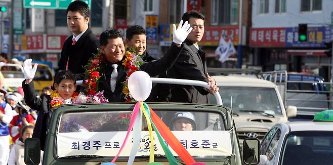 2007년 고향 전남 완도를 찾은 최경주가 아들과 함께 차량을 타고 주민들에게 손을 흔들고 있다. 연합뉴스