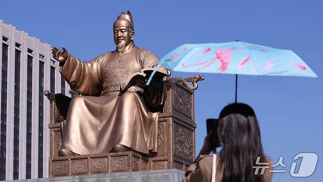 한글날 제정 100주년을 하루 앞둔 8일 서울 종로구 광과문광장에서 한 시민이 세종대왕 동상을 스마트폰에 담고 있다. 올해는 세종대왕의 한글 창제 580돌이며, 한글날 제정 100주년이다. 2026.10.8 ⓒ 뉴스1 박지혜 기자
