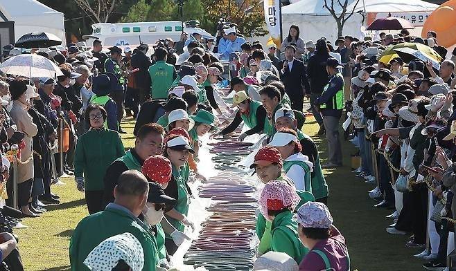 14일 경기&nbsp;이천시 복하천 수변공원에서 열린 ‘제25회 이천쌀문화축제’에서 참석자들이 600m 무지개 가래떡을 만들고 있다. 연합뉴스