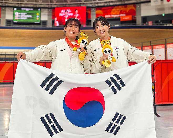 박현미(오른쪽)와 파일럿 김채연이 20일 이즈 벨로드롬서 열린 아시안패러게임 사이클 트랙 여자 1000m 독주(스포츠등급 B) 결선서 금메달을 차지한 뒤 태극기를 펼치고 있다. 사진제공｜대한장애인체육회