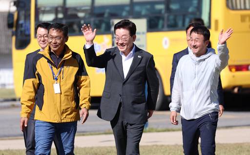 이재명 대통령이 22일 전북 익산 왕궁초에서 열린 가을 체육한마당에 입장하며 학생들을 향해 손을 흔들고 있다. 오른쪽은 더불어민주당 한병도 원내대표. /연합뉴스