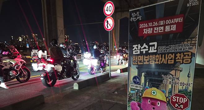 22일 오후 잠수교 전면 보행화 사업으로 오는 26일부터 차량을 전면 통제한다는 안내문 왼쪽으로 오토바이 라이더들이 지나가고 있다. /강정아 기자