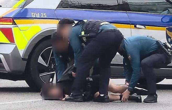 서울 강남대로 차로를 오열하며 걷던 여성이 도로에 주저 앉아 버리자, 경찰이 흔들어 깨우며 인도로 옮기는 모습. [스레드 캡처]
