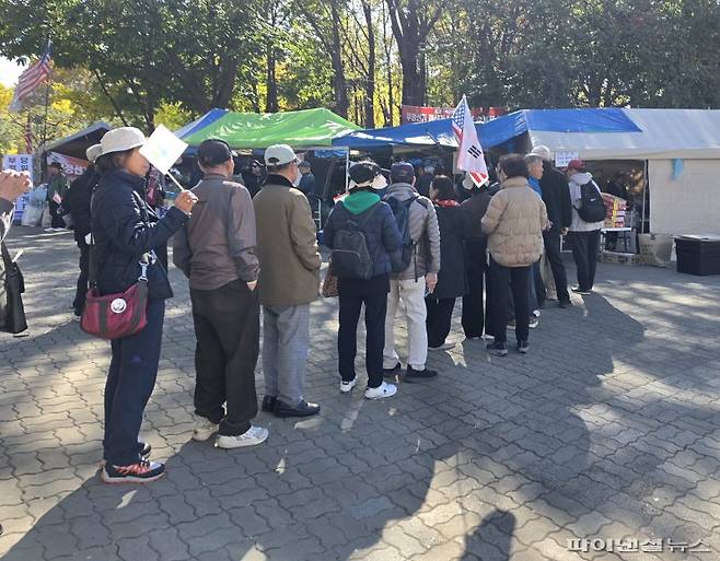이태한 선거관리위원회 특별검사팀의 6·3 지방선거 투표지 공개 검증이 진행된 28일 오후 서울 송파구 올림픽공원 핸드볼경기장 1-3 출입문 인근에서 시위 참가자들이 컵라면 제공 부스 앞에 줄을 지어 차례를 기다리고 있다. 사진= 박성현 기자