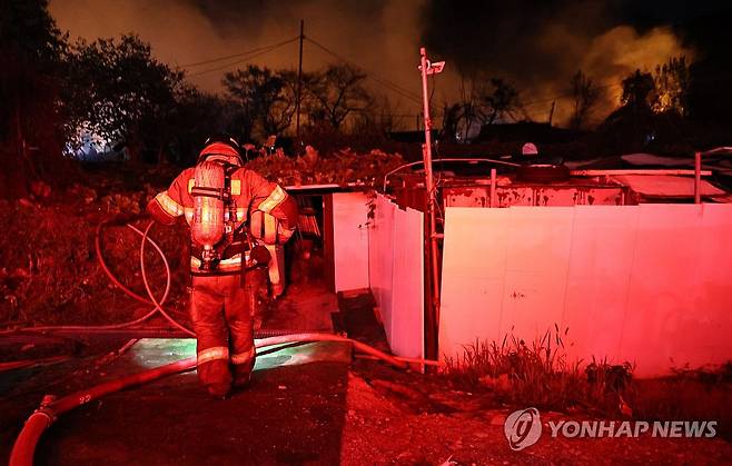 다시 화재 현장으로… (서울=연합뉴스) 김인철 기자 = 27일 화재가 발생한 서울 강남구 구룡마을에서 한 소방관이 진화작업을 위해 장비를 챙겨 다시 현장으로 향하고 있다. 2026.10.27 yatoya@yna.co.kr