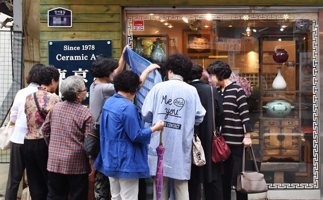 11일 인간문화재의 도예 작품이 진열된 인사동의 한 도예점 앞에서 중년 여성들이 점포에서 내 놓은 스카프를 고르고 있다.