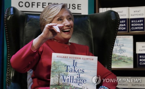 Hillary Clinton holds her book "It Takes A Village" as she sits on stage at the Warner Theatre in Washington, Monday, Sept. 18, 2017, during a book tour event for her new book "What Happened" hosted by the Politics and Prose Bookstore. (AP Photo/Carolyn Kaster)