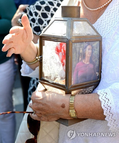 암살당한 탐사보도 기자의 사진이 부착된 양초통을 들고 있는 한 몰타 시민 [AP=연합뉴스]