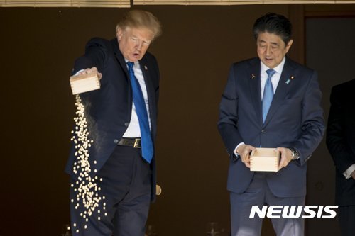 잉어 밥 쏟아붓는 트럼프. 트럼프 이전 아베 총리가 먼저 잉어 밥을 쏟아부어 밥이 든 상자가 비어있다(오른쪽)/사진=AP,뉴시스