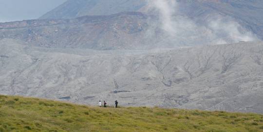 아소산 분화구를 조망할 수 있는 구사센리의 초지 능선 위를 관광객들이 걷고 있다. 뒤로 아소산이 뿜어내는 흰 연기가 보인다.