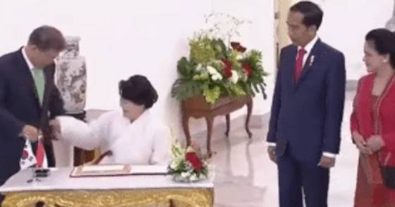 9일 오후 인도네시아 대통령 궁에서 방명록을 작성하기 위해 탁자에 앉은 김정숙 여사. 문재인 대통령에게서 펜을 찾고 있다.