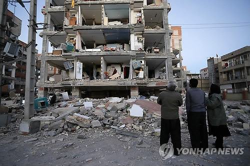 (테헤란 AP=연합뉴스) 13일(현지시간) 이란 북서부 케르만샤주(州) 사르폴-에자하브 마을에서 주민들이 지진으로 부서진 건물을 바라보고 있다.     lkm@yna.co.kr