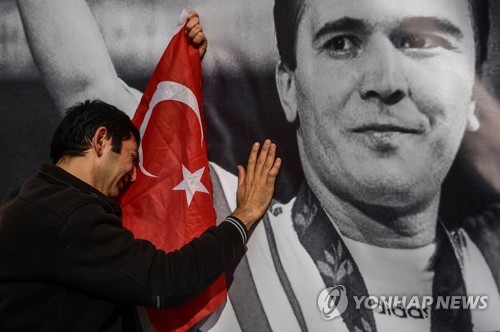 슐레이마놀루의 사진 앞에서 눈물 흘리는 터키 팬 (이스탄불 AFP=연합뉴스) 터키의 한 팬이 18일(현지시간) 나임 슐레이마놀루의 사진 앞에서 눈물을 흘리고 있다. 세계적인 역사였던 슐레이마놀루는 이날 세상을 떠났다.