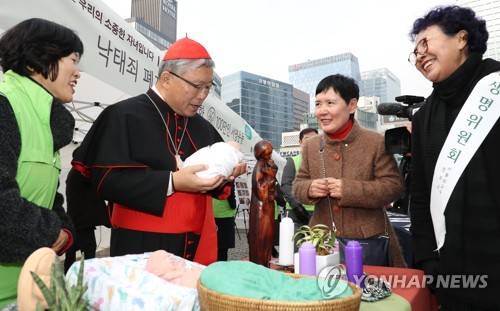 염수정 추기경, '이렇게 어린 생명을' (서울=연합뉴스) 김주형 기자 = 염수정 추기경(왼쪽 두 번째)이 3일 오후 서울 명동성당에서 열린 '낙태죄 폐지 반대를 위한 100만인 서명운동'에 참석해 서명한 뒤 6개월 반이 된 태아의 인형을 안아보고 있다. 2017.12.3