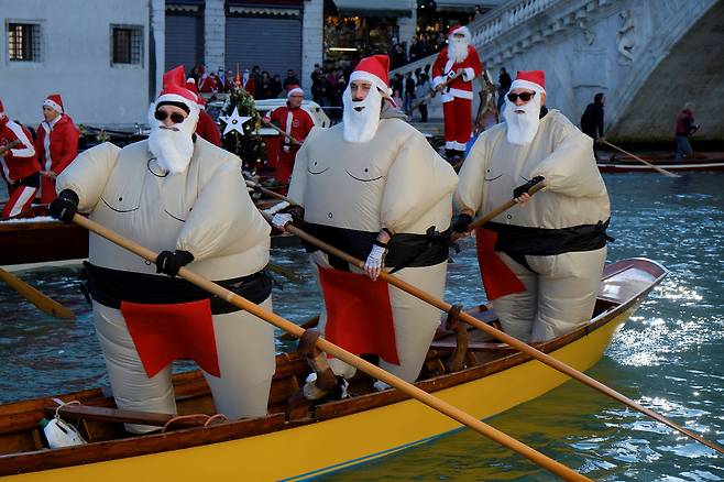 17일(현지시간) 이탈리아 베니스에서 산타 복장을 한 시민들이 배를 타고 있다.[로이터=연합뉴스]