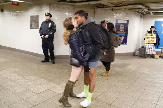 7일 미국 뉴욕에서 한 커플이 "No Pants Subway Ride" 행사에 동참한 후 경찰관이 지켜보는 가운데 키스를 하고 있다. [로이터=연합뉴스]
